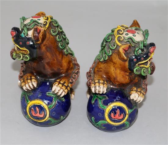 A pair of Chinese polychrome pottery figures of lion-dogs with balls, height 12cm